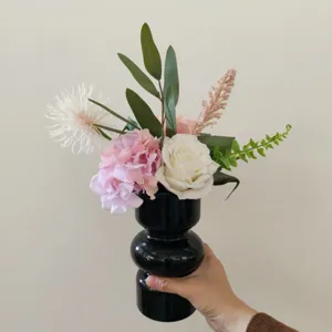 Künstlicher Blumenstrauß in schwarzer Vase, elegante Tischdekoration für das Wohnzimmer.