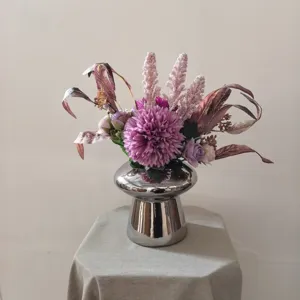 Vue détaillée d'un bouquet de fleurs artificielles violettes modernes dans un vase argenté.