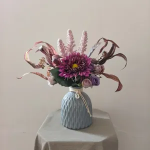 Gros plan détaillé du bouquet de fleurs artificielles violettes dans le vase gris.