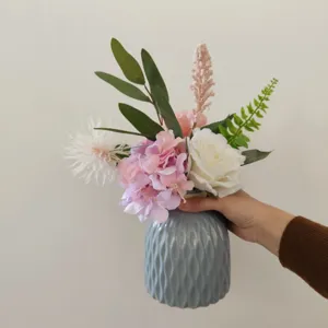 Künstlicher Blumenstrauß Detail, rosa Hortensie und weiße Rose in gerippter grauer Vase.