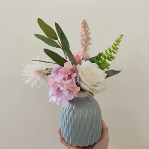 Künstlicher Blumenstrauß Detailansicht mit Seidenblumen in blauer Vase für Heimdekoration.
