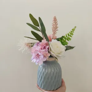 Detailansicht des künstlichen Blumenstraußes in blauer Keramik-Rippenvase für Heimdekor.