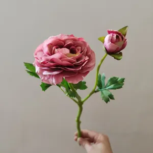 Detail shot of artificial camellia flower branch with one blooming head and a small bud.