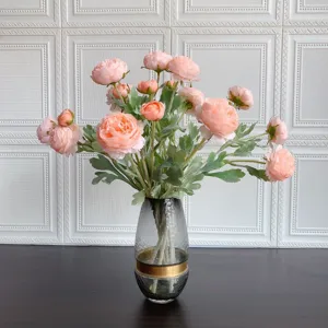 Vista di dettaglio di un bouquet di ranuncoli artificiali in un vaso di vetro decorativo.
