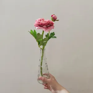 Artificial pink camellia flower in clear glass vase, detail shot for home decor photography.