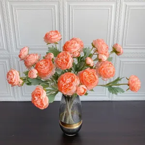 Primo piano dettagliato di un bouquet di ranuncoli artificiali pesca in vaso di vetro decoro.