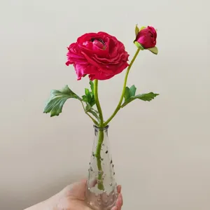 Detail shot of artificial camellia flower with glass vase, perfect for home decor display.