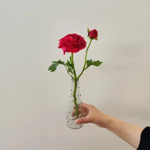Detail shot of artificial camellia flower with clear glass vase, perfect for home decor prop.
