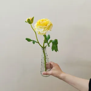 Detailed shot of yellow artificial camellia flower in a clear glass vase for decor.