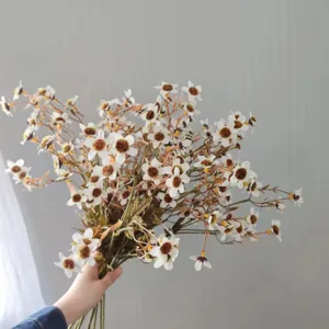Close-up of artificial chamomile flower bouquet in hand, autumn style decor detail shot.
