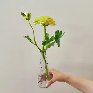 Close-up detail of artificial camellia flower with two heads in a clear glass vase.