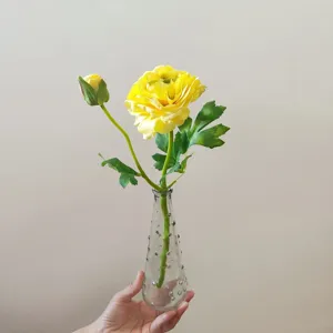 Detail view of artificial yellow camellia flower with glass vase, perfect photography prop.