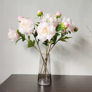 Detailed view of beautiful artificial peony silk flowers arranged in a clear glass vase for decor.
