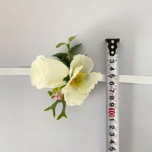 Détail de corsage de poignet de fleur artificielle avec rose blanche et coquelicot.