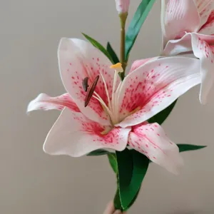 Close-up detail of artificial lily flower with red dots, realistic texture and green leaves.