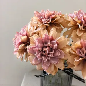 Close-up detail of vintage artificial dahlia flowers with gradient baked edges in glass vase.