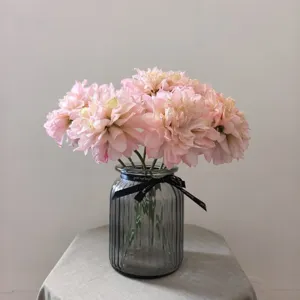 Detailed shot of vintage pink artificial dahlia flowers arranged in a ribbed grey glass vase.