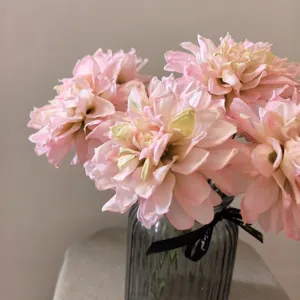 Detail view of artificial pink dahlia flower bouquet in a grey glass vase with ribbon.