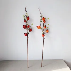 Dettaglio di ramo di melograno artificiale, perfetto per decorazioni domestiche e vetrine.