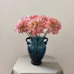 Close-up detail of retro artificial dahlia flowers in a blue glass vase for home decor.