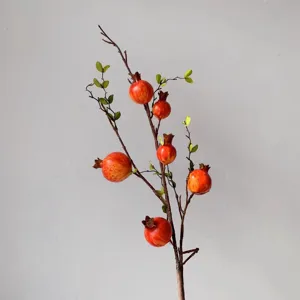 Dettaglio ramo di melograno artificiale, decorazione realistica di frutta rossa per casa e vetrina.