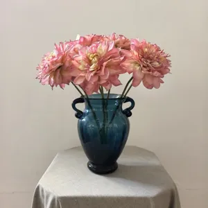 Detailed view of artificial pink dahlia flowers arranged in a vintage blue glass vase.