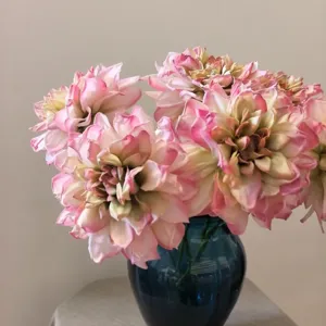 Detailed view of vintage pink artificial dahlia flowers in a blue glass vase arrangement.