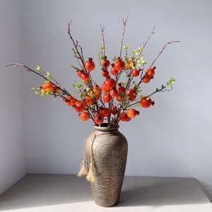 Dettaglio ramo di melograno artificiale, elegante accessorio decorativo per interni.