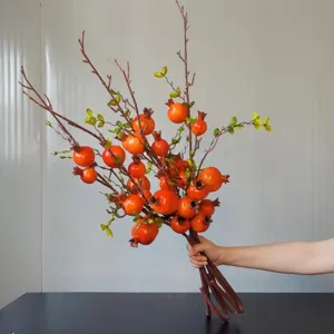 Primo piano dettagliato di rami di melograno artificiali, frutti rossi vivi per decoro.