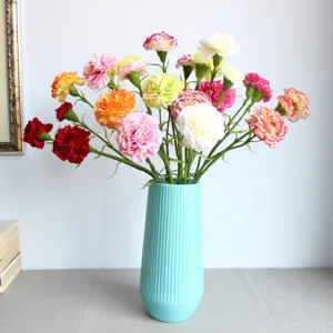 Detail view of artificial carnation bouquet in blue ribbed vase, home decor floral arrangement.