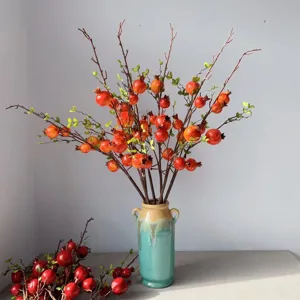 Rami di melograno artificiali con vaso in ceramica per decorazioni domestiche e display.