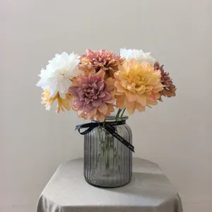 Detailed close-up view of vintage artificial dahlia flowers arrangement in glass vase.