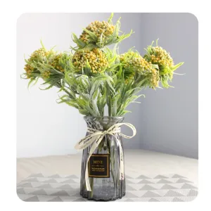 Artificial fern and fruit flower bouquet with a clear glass vase for home decoration use.