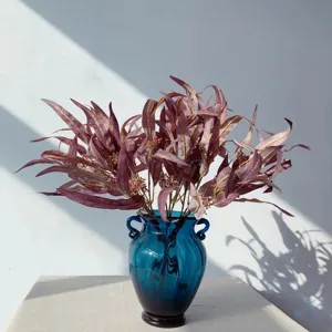 Bouquet de fleurs d'eucalyptus artificiel avec vase en verre, détail pour déco maison.