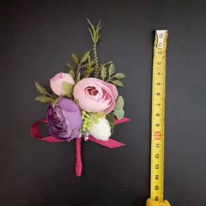 Botonero de flores artificiales rosa y morado con cinta para la boda del novio.