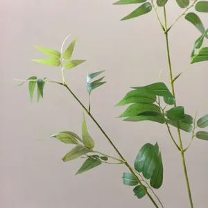 Close-up detail of artificial bamboo branches, showing realistic green leaves and stems for decor.