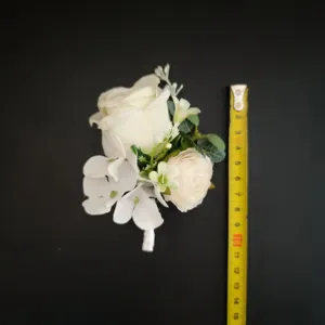 White artificial flower boutonniere wedding groom corsage with size reference tape measure.