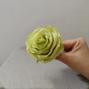 Detailed close-up view of a green artificial rose flower head, perfect for cake and hat decoration.