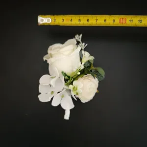 White artificial rose flower boutonniere detail view wedding groom corsage floral accessory.