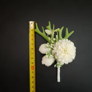 Close-up detail view of the white artificial boutonniere with green leaf decor and measuring tape.