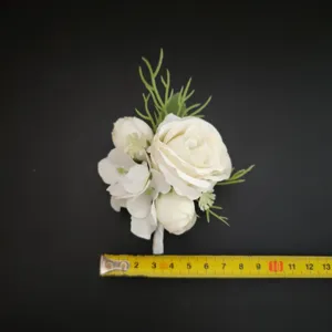 White artificial rose boutonniere detail shot, perfect wedding groom and bridesmaid floral accessory.