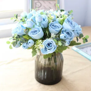 Artificial blue rose bouquet with eucalyptus leaves in glass vase for home decor wedding.