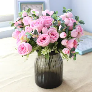 Artificial pink rose eucalyptus flower bouquet detail view with dark glass vase for decor.
