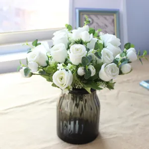 White artificial rose bouquet with eucalyptus leaves in a glass vase for home decor DIY.