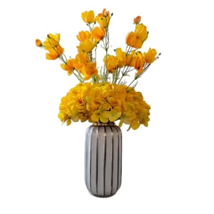 Bouquet de fleurs artificielles jaunes avec vase rayé pour la décoration de table et salon.