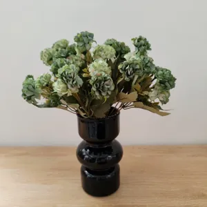 Schöner künstlicher Blumenstrauß mit schwarzer Keramikvase für stilvolle Heimdekoration
