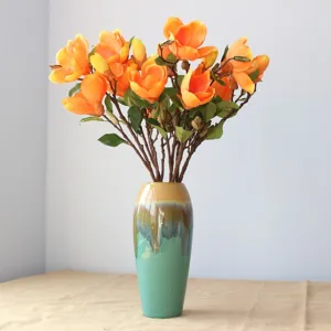 Schöner künstlicher Orangen-Magnolien-Blumenstrauß mit eleganter Keramikvase für die Raumdeko.