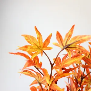 Close-up detail van kunstmatige esdoornbladeren herfst oranje bladeren tak voor decoratie
