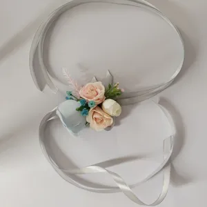 Closeup detail of artificial rose wrist corsage with elegant silver ribbon for wedding.