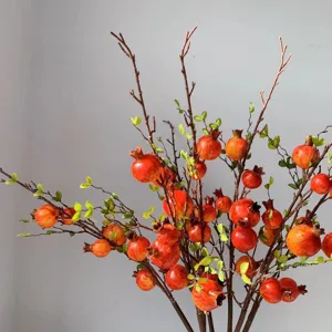 Primo piano del dettaglio del ramo di melograno artificiale, frutti rossi realistici per decoro.